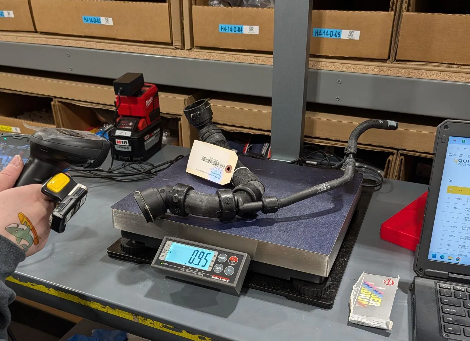 A bent rubber hose with a barcode tag on the S1 scale, under the S1 mast; the operator holds the wireless scanner that starts the capture