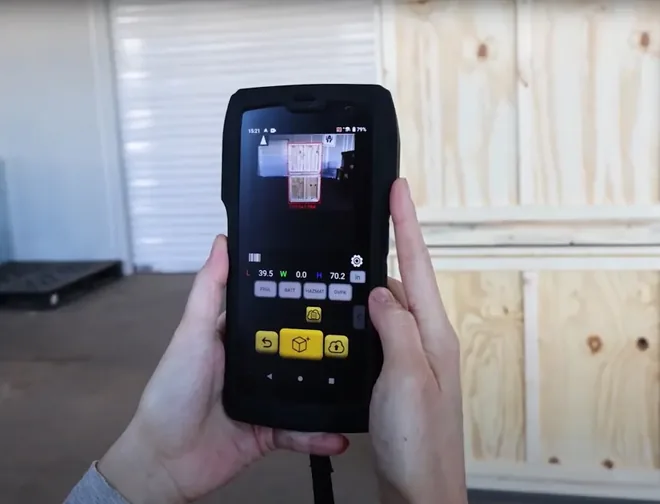 Hands holding the M2 up to a crate, the Pallets app on screen